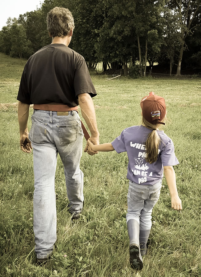 A man and a girl holding hands in a field.