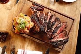 A steak is sitting on a wooden table.