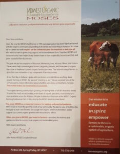 A letter with a picture of a cow in the grass.